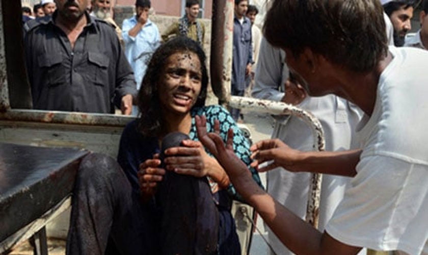 Kashmala Munawar segura sua perna, após ser socorrida próximo à igreja bombardeada no Paquistão. (Foto: British Pakistani Christian Association)