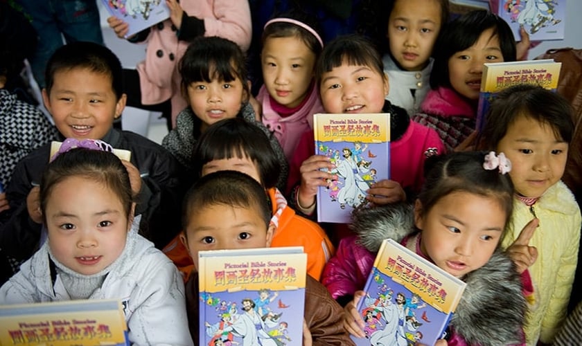 Crianças recebem literatura cristã infantil, distribuída por missionários, na China. (Foto: American Bible Society News)