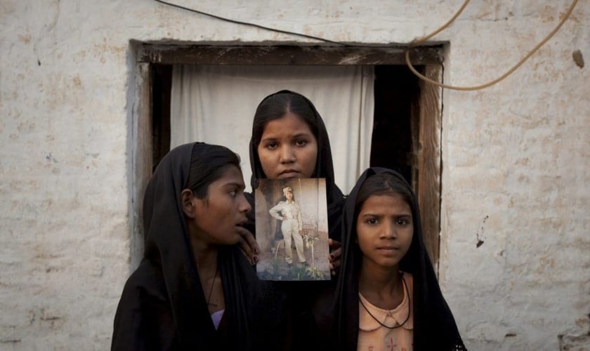 As filhas de Asia Bibi seguram uma imagem da mãe. (Foto: Reprodução).