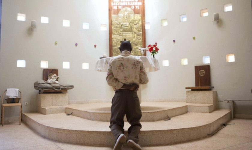 Homem ora diante de altar em igreja, em Uganda. (Foto: Reuters)