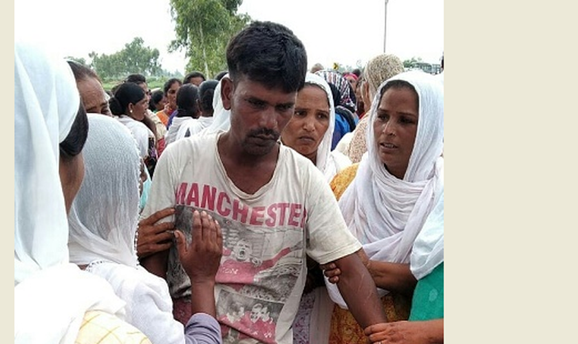 O pai de Anjali Masih sendo confortado por vizinhos. (Foto: WWM)
