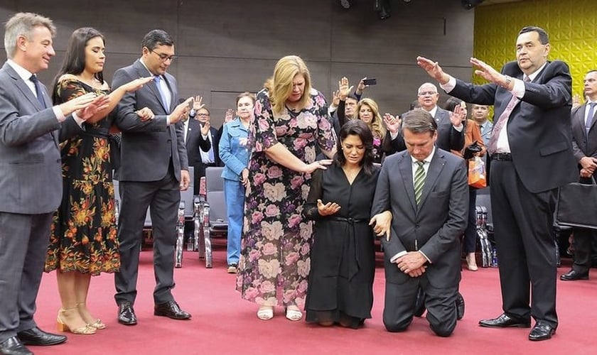 Jair Bolsonaro e sua esposa, Michelle, se ajoelham para que líderes orem pelo governo, durante culto da Assembleia de Deus, em Manaus. (Foto: BNC Amazonas)