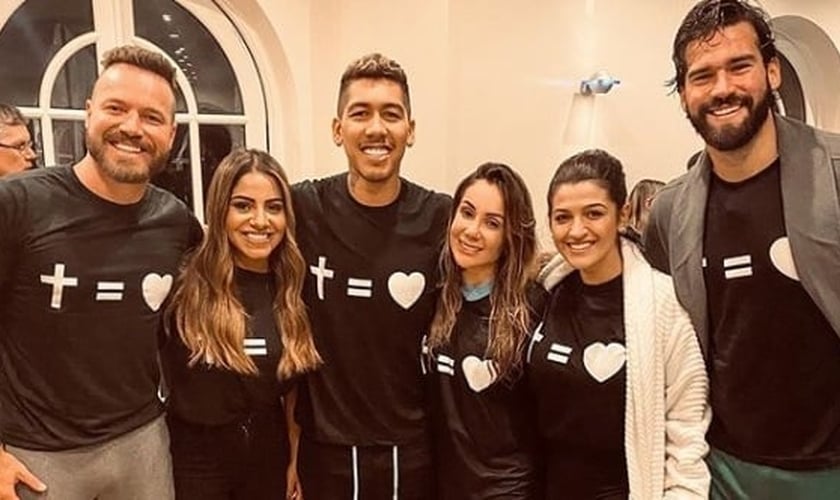 Em seu batismo, Roberto Firmino contou com a presença de sua esposa, Larissa Pereira, do parceiro de time Alisson Becker e da cantora Gabriela Rocha. (Foto: Instagram)