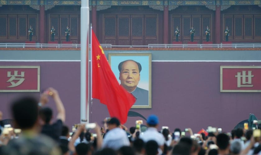 Visitantes acompanham uma cerimônia de hasteamento da bandeira com a imagem de Mao Tsé Tung ao fundo, na praça Praça da Paz Celestial, em Pequim, em julho de 2018. (Foto: CHINA STRINGER NETWORK/REUTERS/Newscom)