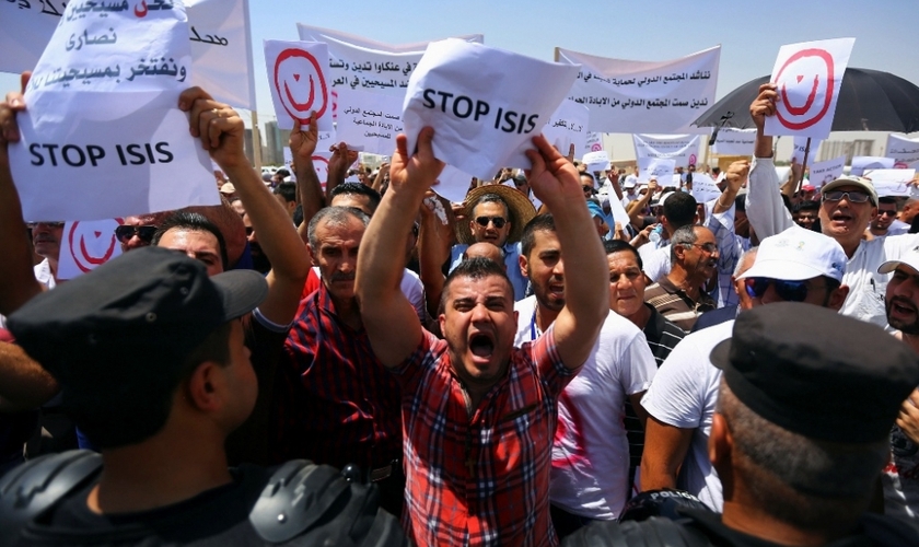 Manifestantes seguram placas e cartazes em protesto contra o Estado Islâmico no Iraque. (Foto: Reuters)