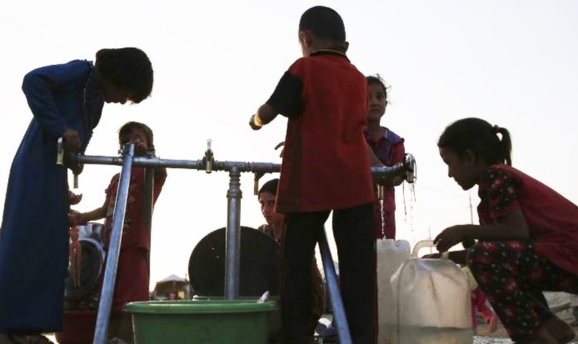Crianças pegam água em campo de refugiados de Erbil, Iraque. (Foto: Reuters)