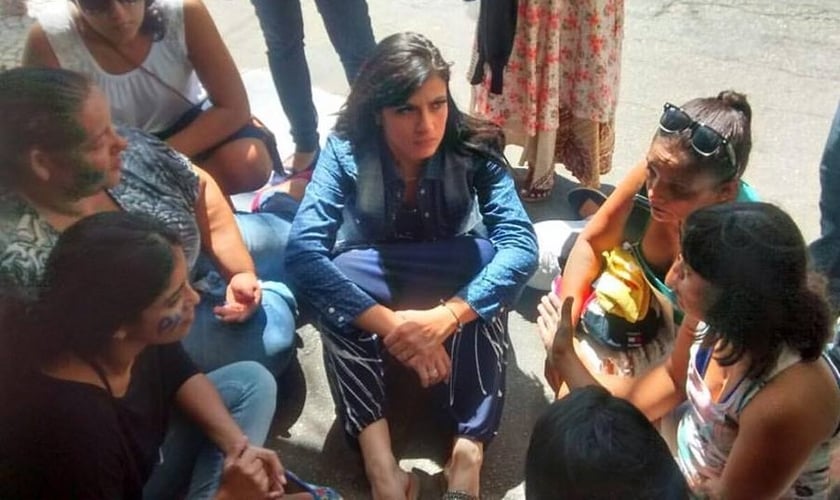 Fernanda Brum se assenta no chão para conversar com esposas de PMs em frente ao Sexto Batalhão Policial Militar (Tijuca), no RJ. (Foto: Facebook)