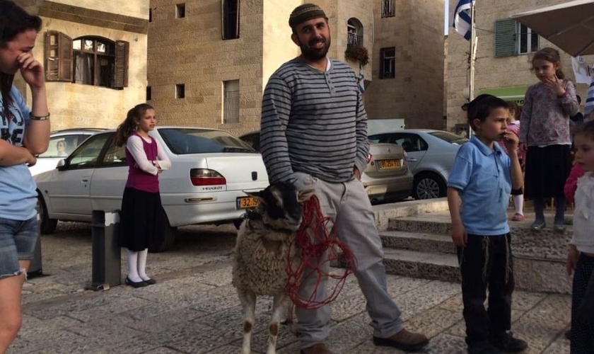 Homem segura cordeiro separado para simulação de sacrifício de Páscoa. (Foto: Times Of Israel)