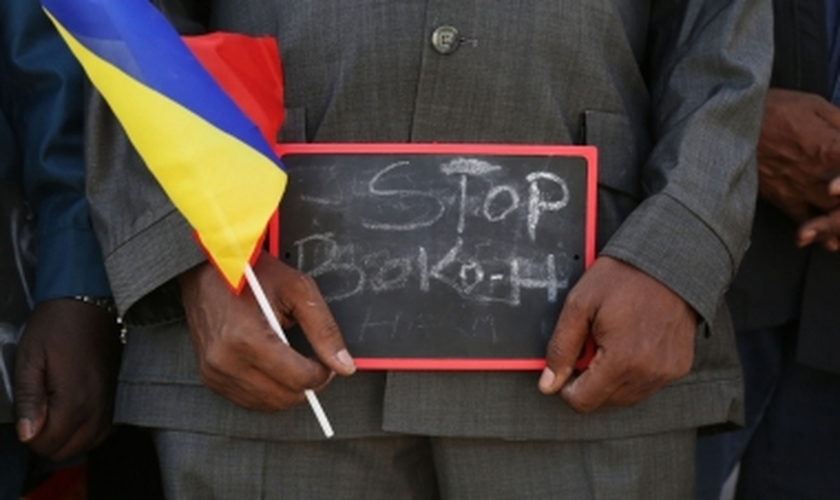 Homem segura uma pequena placa que diz "Pare, Boko Haram", em um evento para apoiar as tropas militares de Chade