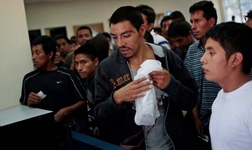 Imigrantes ilegais aguardam enquanto recebem seus pertences e processam sua volta ao aeroporte de La Aurora (Guatemala), de onde saíram.