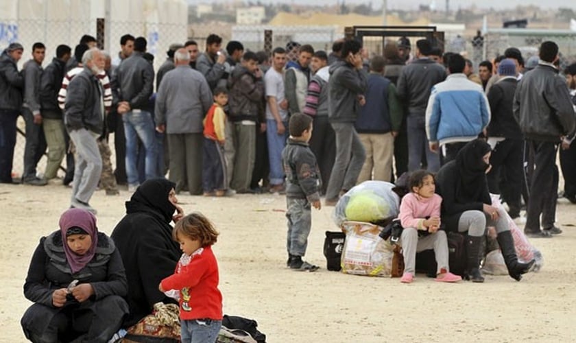 Refugiados aguardam do lado de fora de um campo, na Jordânia. Imagem do final de 2013. (Foto: Muhammad Hamed/Reuters)