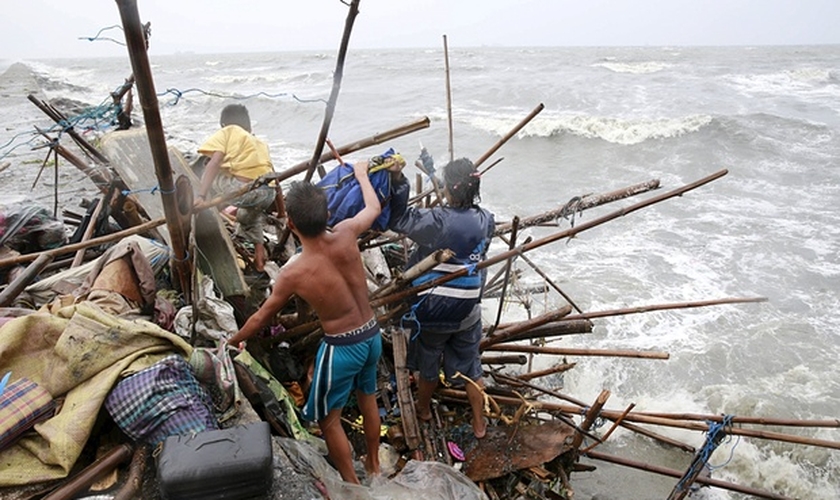 Uma família que vive na baía de Manila tenta achar pertences que possam ser recuperados, após a sua casa ter sido destruída por fortes ventos trazidos pelo tufão Koppu neste domingo, 18/10. (Foto: Romeo Ranoco/Reuters)
