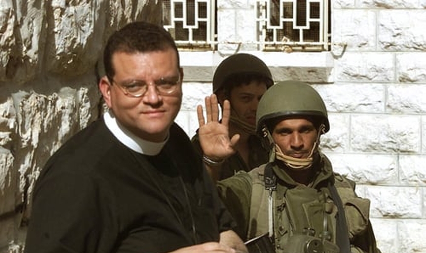 Um soldado israelense (R) recebe o Rev. Andrew White, o "vigário de Bagdá", enquanto ele tenta visita a Igreja da Natividade, em Belém, no dia 14 de abril de 2002. (Foto: Reuters/Oleg Popov)