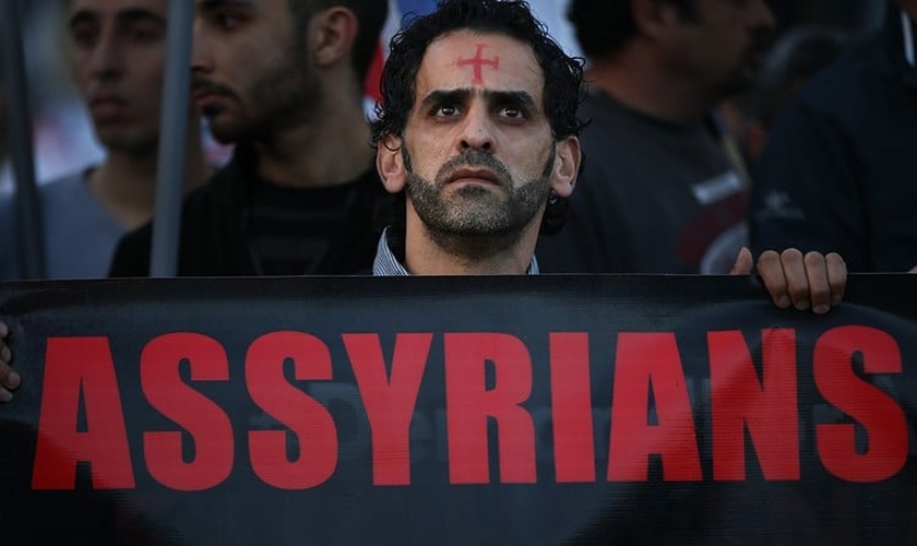 Um homem assírio caminha durante um protesto unido a centenas de pessoas. (Foto: Reprodução/The Wall Street Journal)