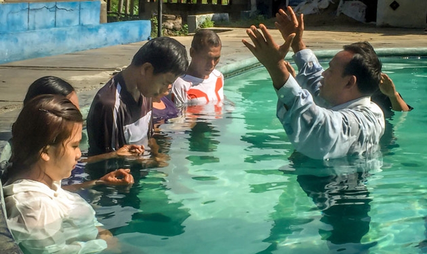 Pastor faz oração durante batismo de novos convertidos, em país da Ásia. (Foto: Christian Aid Mission)