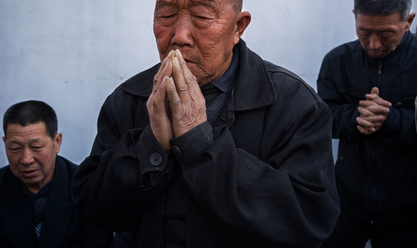 Chineses orando em uma igreja subterrânea no quintal de uma casa. (Foto: Adam Dean/Panos)