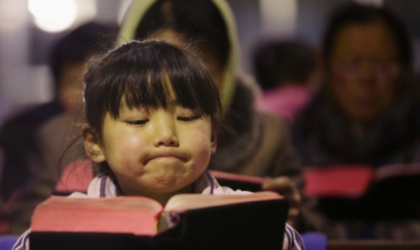 Criança lê Bíblia em igreja no vilarejo de Gaojiabao, na China. (Foto: Jason Lee/Reuters)