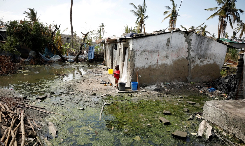 Criança ao lado de poças de água parada em Beira, Moçambique, nesta quarta-feira (27) (Foto: Mike Hutchings/Reuters)