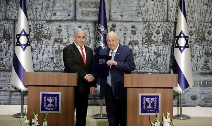 O presidente de Israel, Reuven Rivlin, dá as mãos ao primeiro-ministro Benjamin Netanyahu, como o escolhido para permanecer no cargo e formar governo no país. (Foto: Sebastian Scheiner/AP)