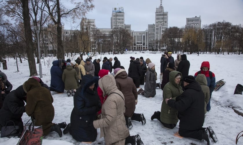 Ucranianos se ajoelham e oram na neve em praça da cidade de Kharkov (Foto: Reprodução/IMB)