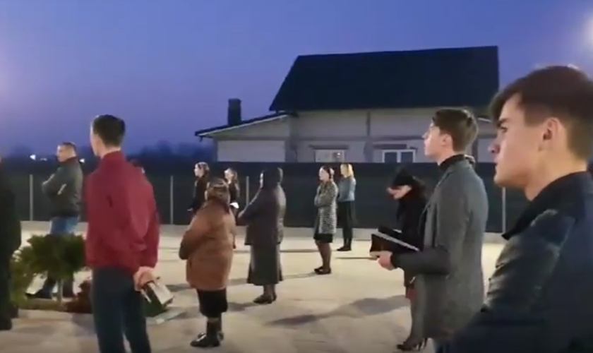 Membros da Igreja Cristã após o Evangelho de Sião, na vila de Prelipca, reunidos no estacionamento. (Foto: Reprodução/YouTube)