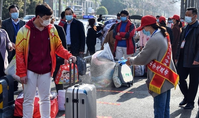 Voluntária aplica desinfetante sobre a bagagem de um aluno em Bozhou, na província de Anhui, no leste da China. (Foto: AFP)