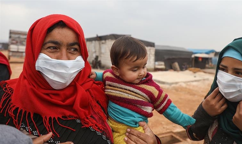 Mulheres usam máscaras em um campo para deslocados na província de Idlib. (Foto: Aaref Watad / AFP)