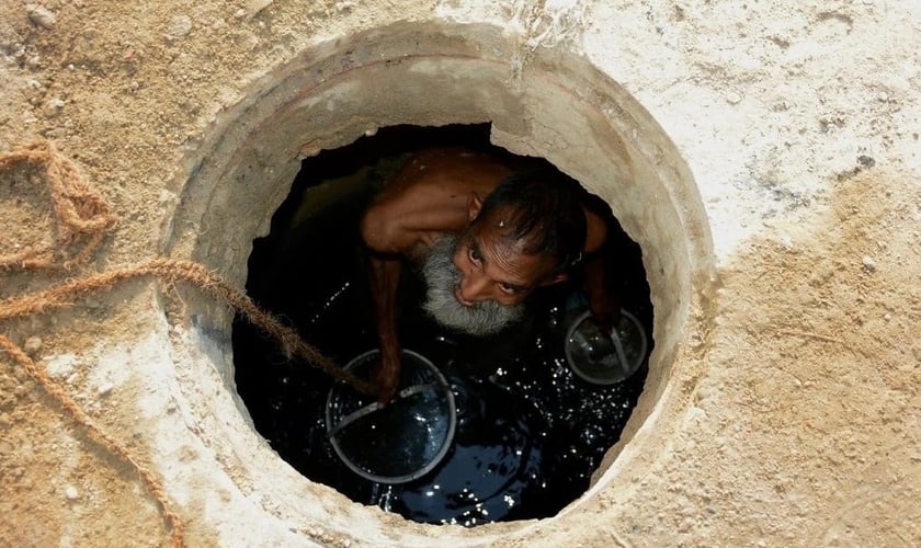 Jamshed Eric trabalhando em um esgoto em Karachi no ano passado. (Foto: Reprodução/NYT)