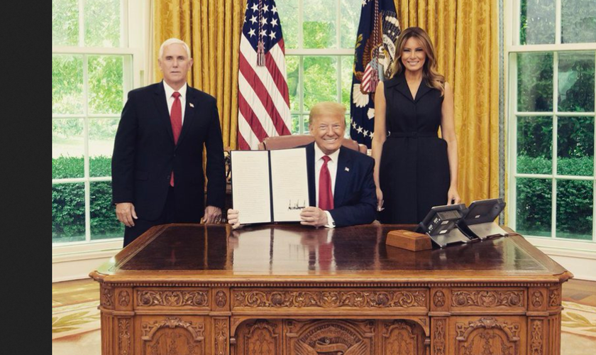 Donald Trump exibe a assinatura da ordem, entre a primeira-dama Melania e o vice Mike Pence. (Foto: Reprodução/Twitter)