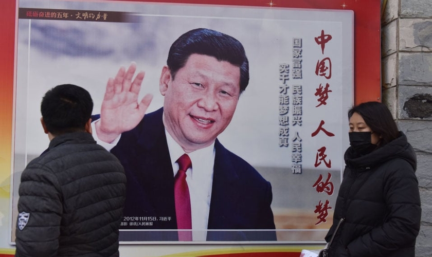 Pessoas passam por um pôster do presidente chinês Xi Jinping ao lado de uma rua em Pequim. O controle cada vez maior de Xi Jinping sobre a China já rendeu ao líder comparações com Mao Tsé Tung. (Foto: AFP / GREG BAKER)