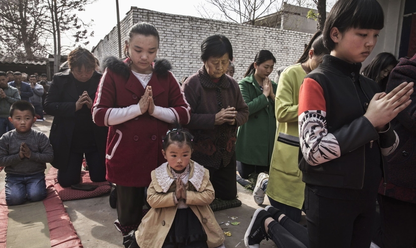 Cristãos chineses oram ajoelhados durante um culto de Páscoa em uma igreja não oficial. (Foto: Getty Images / Kevin Frayer)