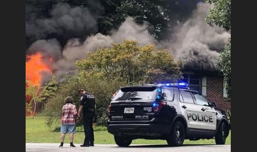 Sem perceber, policial é fotografado orando com mulher que perdeu casa em incêndio. (Foto: Reprodução / Facebook)