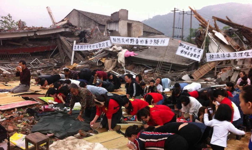 Cristãos se ajoelham nos escombros de uma igreja demolida . (Foto: Reprodução / China Aid)