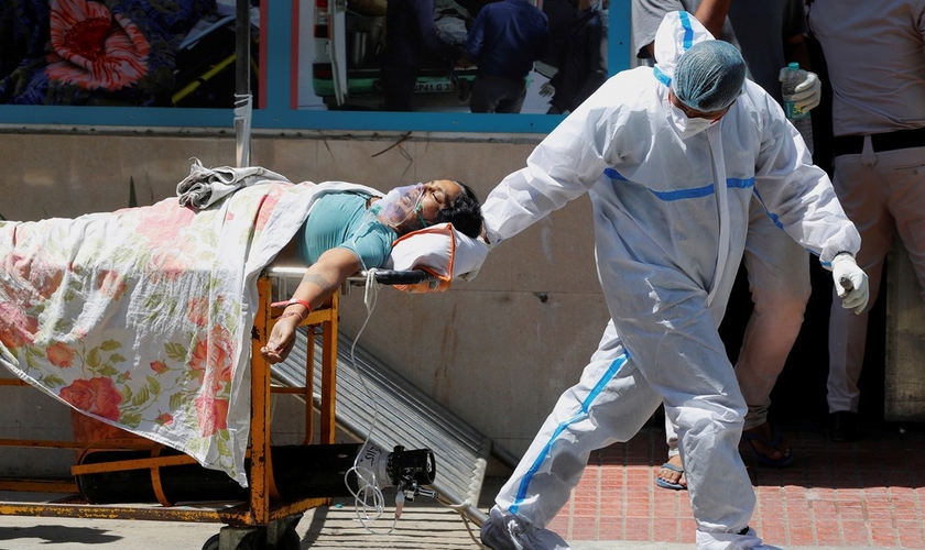 Profissional de saúde leva paciente com Covid-19 em hospital de Nova Delhi, na Índia, neste sábado (24). (Foto: Adnan Abidi/Reuters).