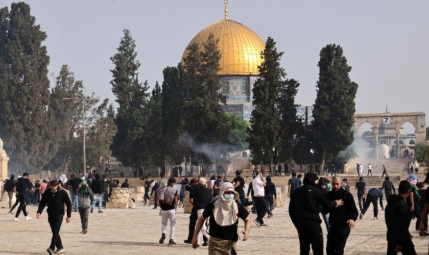 Palestinos correm para se proteger do gás lacrimogêneo disparado pelas forças de segurança israelenses no complexo da mesquita de Al-Aqsa, Jerusalém, em 10 de maio de 2021. (Foto: Ahmad Gharabli/ AFP via Getty Images)