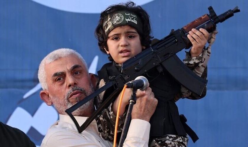Líder do Hamas, Yahya Sinwar, segura o filho de um membro que foi morto no confronto com Israel. (Foto: Emmanuel Dunand/AFP)