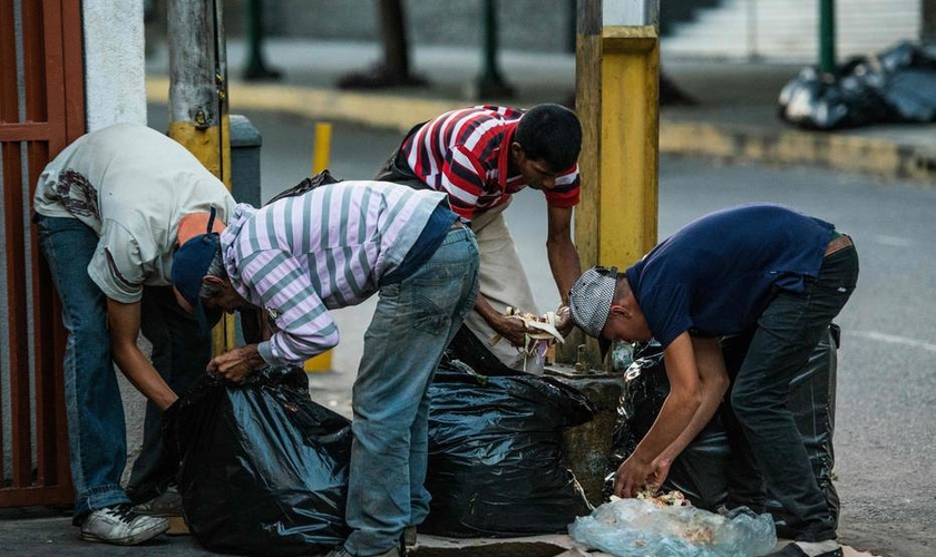 Pessoas vasculham lixo em busca de comida nas ruas de Caracas. (Foto: Getty Images)