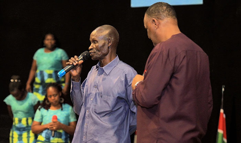 Homem conta seu testemunho após receber oração do Pr. Gerald Mwebe, no culto de Páscoa. (Reprodução / UGCN)