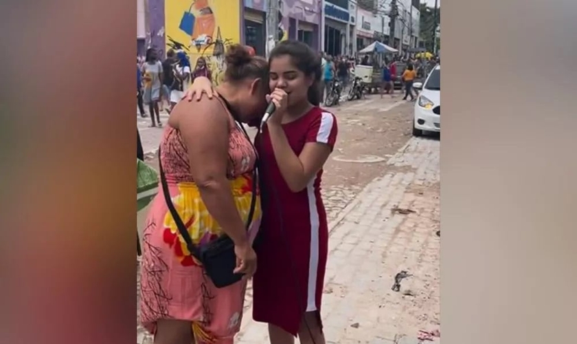 Kemily Maciel abraça mulher que se emociona enquanto ela canta uma música gospel em Fortaleza. (Foto: Arquivo pessoal)