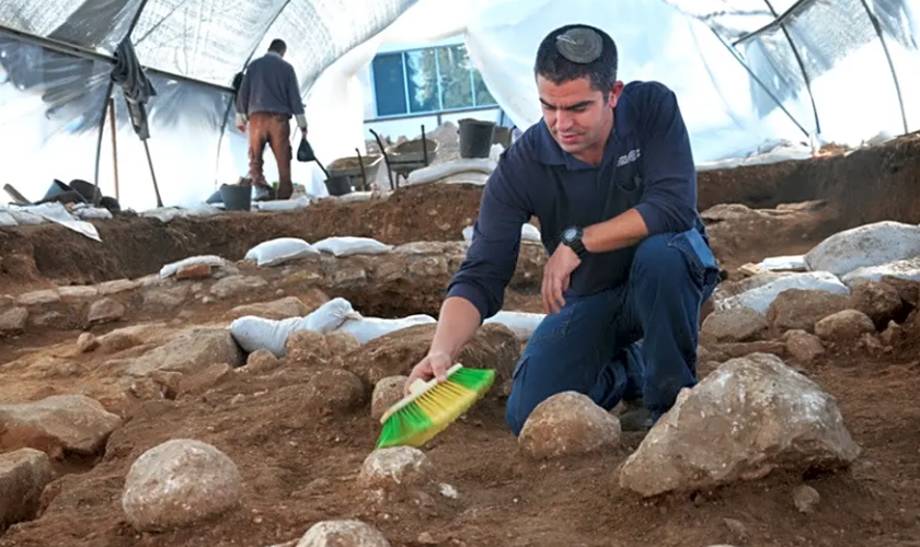 Kfir Arbiv, diretor de escavação da Autoridade de Antiguidades de Israel, limpa uma pedra balista no Complexo Russo. (Foto: Yoli Schwartz/Israel Antiquities Authority)