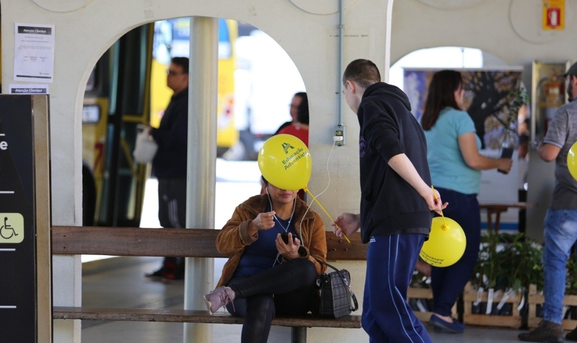 Estudante entrega balão e conversa com passageira no terminal de ônibus. Alunas posam para foto durante mobilização em semáforos. (Foto: Paulo Ribeiro)