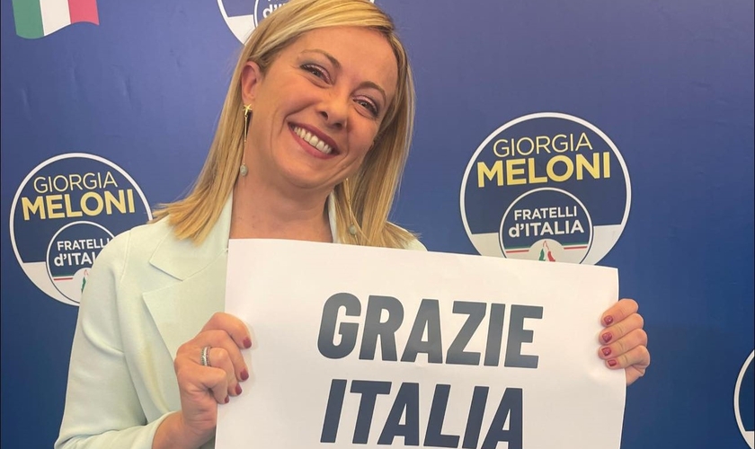 Giorgia Meloni durante discurso à imprensa, segurando placa ‘Obrigada Itália’. (Foto: Reprodução/Facebook/ Giorgia Meloni)