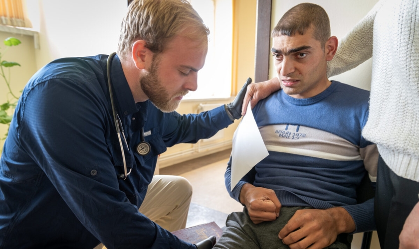 O médico Austin Calhoun ora com um paciente com paralisia cerebral. (Foto: IMB).