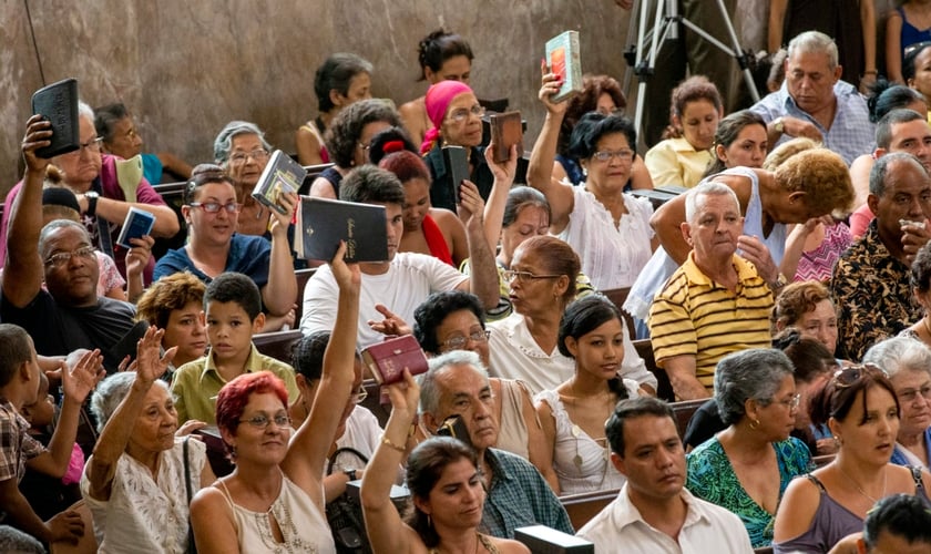 Evangélicos de uma igreja cubana erguem suas Bíblias durante o culto. (Foto: IMB)