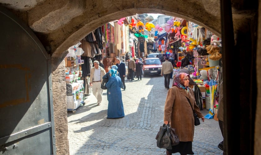 Homens e mulheres caminham por um mercado que vende roupas, alimentos e artigos para o lar em um bairro de Istambul, Turquia. (Foto: IMB)