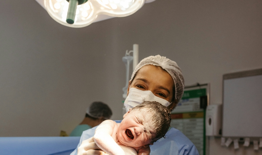 Profissional de saúde segura recém-nascido instantes após o parto. (Foto: Jonathan Borba/Unsplash)