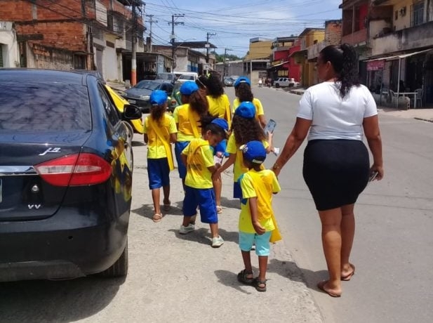 Crianças se vestem como carteiros para entregar mensagens da Bíblia, no Rio